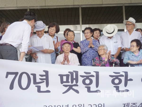 22일 오후 제주지방법원 앞에서 임재성·김세은 변호사가 지난 21일 4·3형사보상 판결을 받은 수형인들에게 결정문을 나눠주고 있다. (사진=조수진 기자)