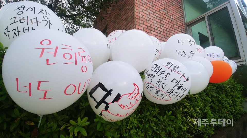 ​"(원희룡 지사는) 평화로운 마을에 날벼락 치지 마라" 선흘2리 주민들은 24일 저녁 마을 복지회관 앞에서 정oo 이장을 규탄하는 문회제를 열었다. 주민들은 복지회관 화단 한 켠에 풍선을 꽂고 원희룡 제주지사를 비판하는 메시지를 담았다.(사진=김재훈 기자)​