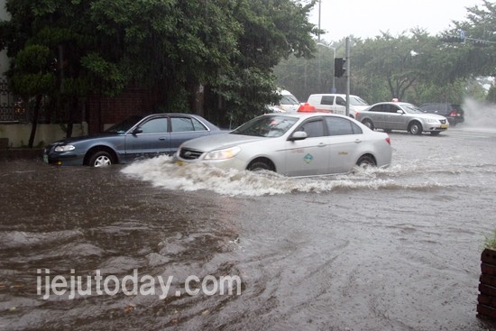 제주시 연동 모 편의점 앞 도로. 갑자기 쏟아진 폭우로 잠겨 있는 도로를 차량들이 위태위태하게 지나가고 있다.<문춘자 기자>