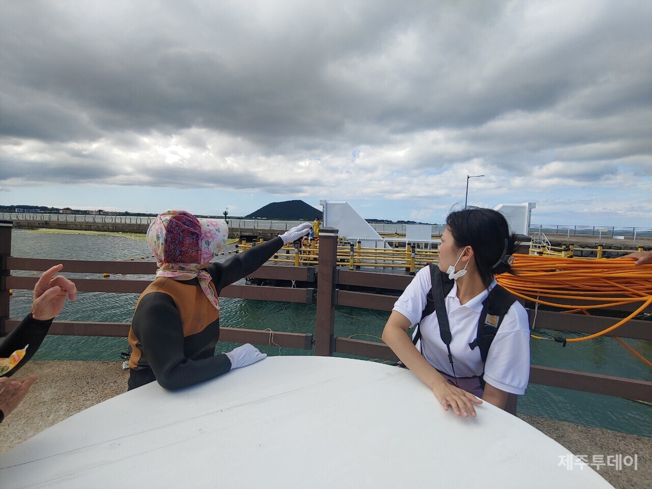시흥리의 해녀가 시흥리에 위치한 부유식 해중전망 전망 시설을 가리키고 있다. 해녀가 가리키는 흰색 통로를 따라 내려가면 바닷속 전망이 펼쳐진다.(사진=김재훈 기자)