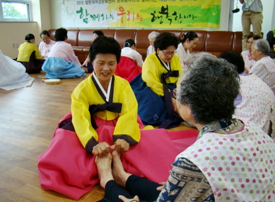 민요동아리 회원들이 노형지소 치매주간보호센터에서 어르신들의 발마사지를 하고 있다. (제주투데이 DB)