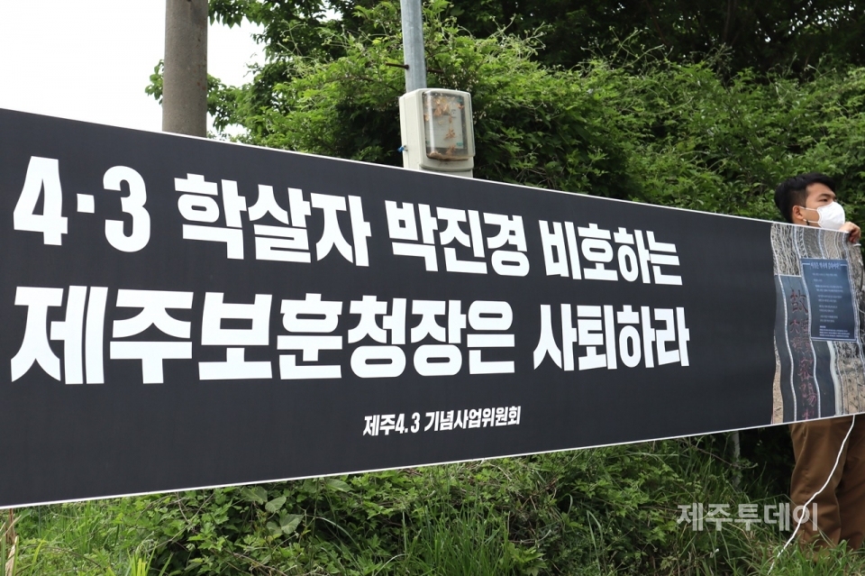 지난 5월20일 제주특별자치도 보훈청이 ‘4·3 도민 학살 주역’이라 평가 받는 박진경 추도비에 씌운 철창 조형물 철거 현장 맞은편에서 4·3단체들이 현수막을 들고 시위하고 있다. (사진=조수진 기자)