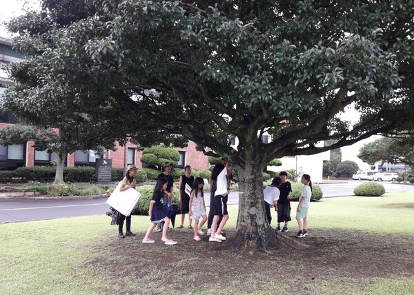 제주기후평화행진은 지난 16일 서귀포시 동홍동 소재 서귀포학생문화원에서 8번째 행진을 진행한 가운데, 참가자 중 어린이들이 서귀포학생문화원 잔디광장에 위치한 나무 아래에서 이야기를 하고 있다.  (사진=황용운 제공)