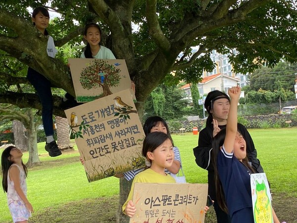 제주기후평화행진은 지난 16일 서귀포시 동홍동 소재 서귀포학생문화원에서 8번째 행진을 진행한 가운데, 참가자 중 어린이들이 서귀포학생문화원 잔디광장에 위치한 나무 아래에서 기후평화를 외치고 있다. (사진=황용운 제공)