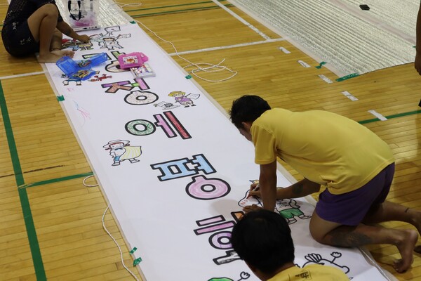 22일 서귀포시 강정동 제주해군기지에서 출발, 제주시청까지 걷는 '2024 제주생명평화대행진'이 진행된 가운데, 1일차 숙소인 서귀포시 남원생활체육회관에서 참여자가 현수막에 색칠하고 있다. (사진=박지희 기자)