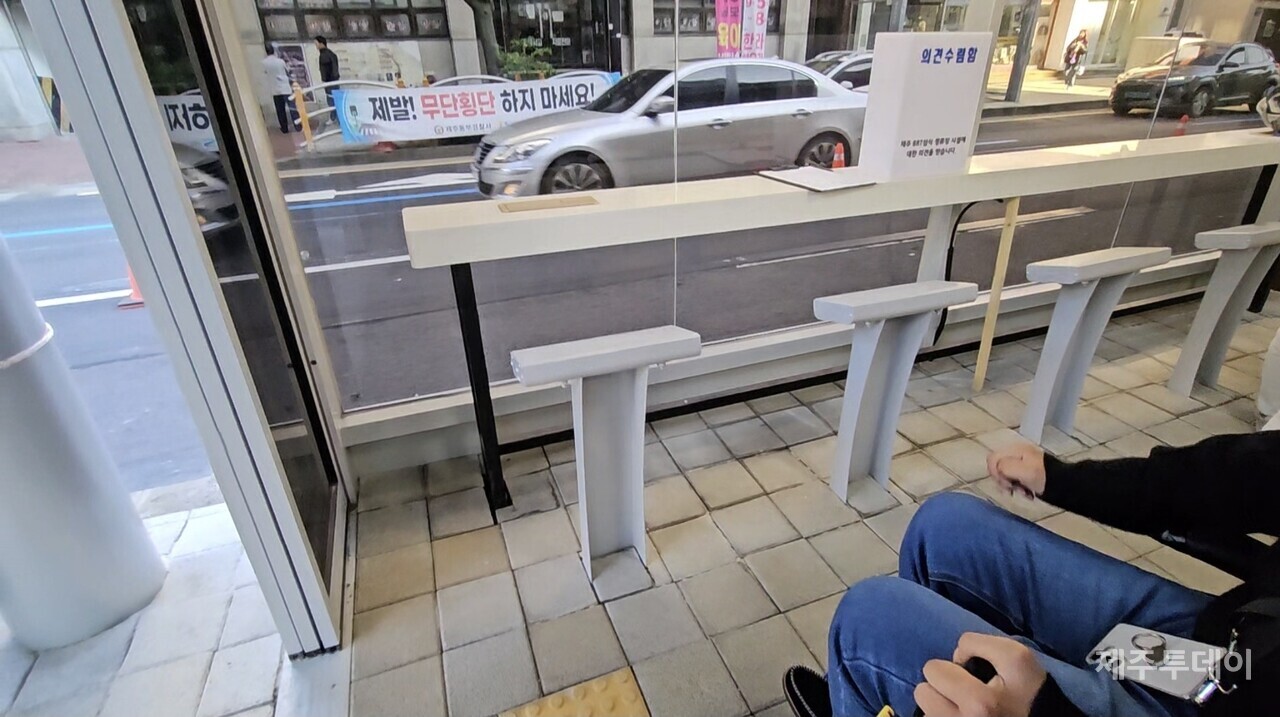 섬식정류장 내부의 테이블과 의자. 입구 점자블록과 가까운 곳에 의자가 바닥에 고정 설치돼 있다. 휠체어 이용자가 이용할 수 있는 테이블은 없다. 휠체어 이용자를 위한 별도의 대기 공간도 보이지 않는다.(사진=김재훈 기자)