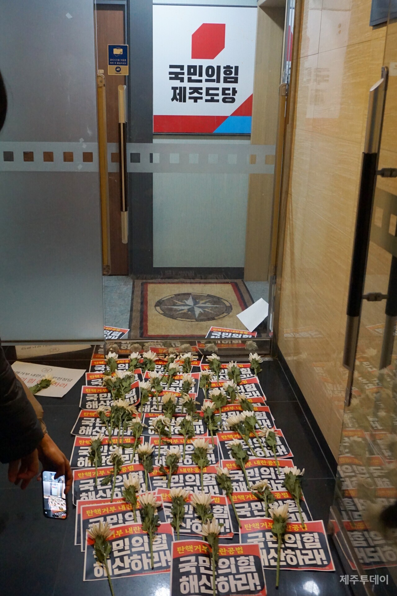국민의힘 제주도당 사무실 앞에 '탄핵거부 내란공범 국민의힘 해산하라'는 피켓과 국화꽃이 높여 있다. (사진=양유리 기자)