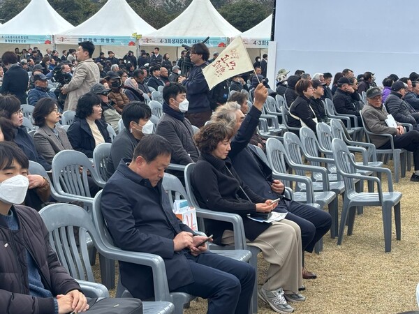   추념식에 참여했던 한 참가자는 한덕수 권한대행 발언 도중  윤석열  탄핵 문구가 적힌 손깃발을 들고 있다. 